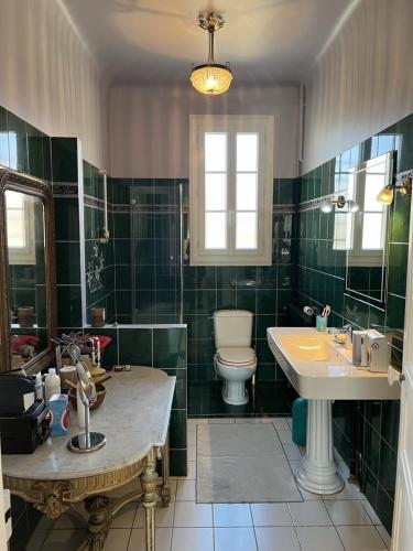 La salle de bains carrelée de couleur verte est pourvue d'un lavabo et de toilettes. dans l'établissement Vallons Bayonne - Aritxague - Maison - piscine, à Bayonne