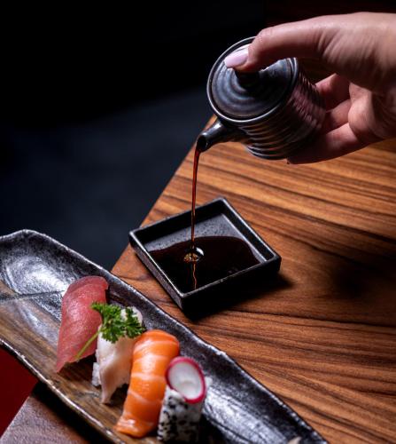 a person is pouring sauce into a plate of sushi at Mövenpick Hotel Geneva in Geneva