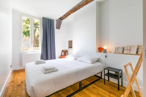 une chambre blanche avec un lit et une fenêtre dans l'établissement Orangerie Jeannin, à Dijon