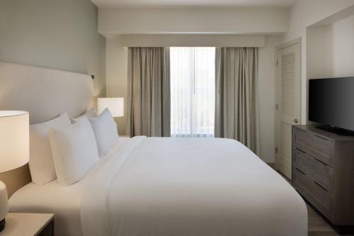 德斯坦的住宿－聖丹斯汀格蘭德大道住宿酒店，酒店客房设有一张白色大床和一台电视。