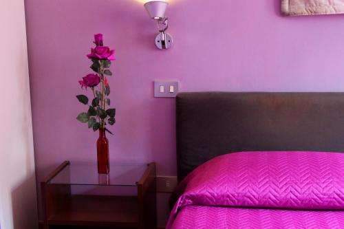 a red vase with pink roses in a bedroom at B&B Basilica Square in Rome