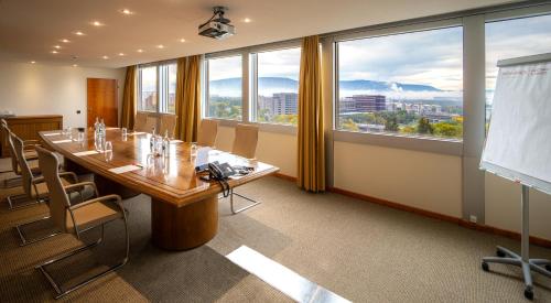 a conference room with a table and a projection screen at Mövenpick Hotel Geneva in Geneva