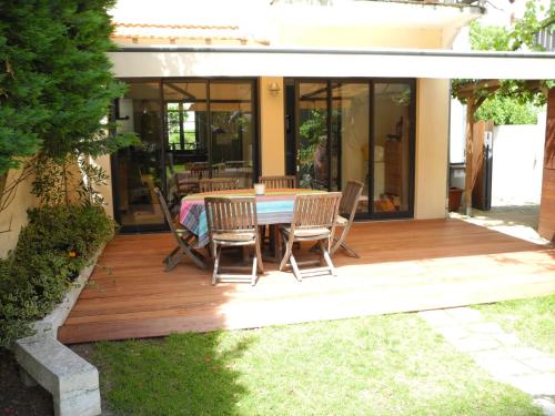 une terrasse en bois avec une table et des chaises dessus dans l'établissement Villa Cantemerle, 3 chambres, jardin, à Arcachon