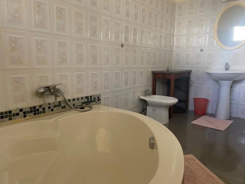 a white bathroom with a tub and a sink at Hotel Le Littoral Des Almadies in Dakar