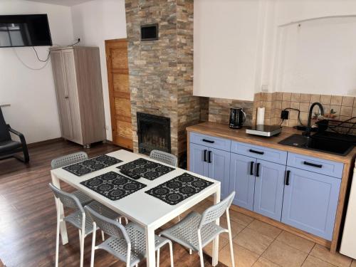cocina con mesa, sillas y chimenea en Kwatery u Jarka z ogrodem i parkingiem, en Jelenia Góra