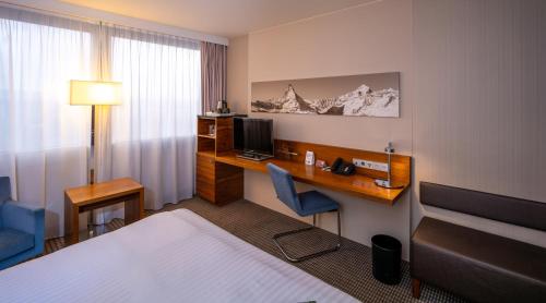 a hotel room with a bed and a desk with a computer at Mövenpick Hotel Geneva in Geneva