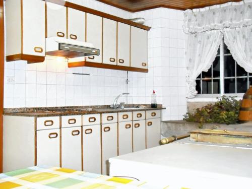 una cocina con armarios blancos y fregadero en 4 bedrooms house with furnished garden at Ourol en Merille