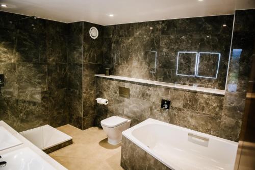 uma casa de banho com uma banheira, um WC e um lavatório. em Crow Wood Hotel & Spa Resort em Burnley