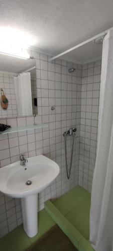 a white bathroom with a sink and a shower at Letos Apartment Sky in Kavála