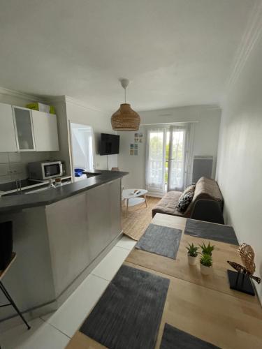 une cuisine et un salon avec un canapé et une table dans l'établissement Appartement Vue mer et espaces verts proche Deauville Traveller Awards 2025, à Blonville-sur-Mer