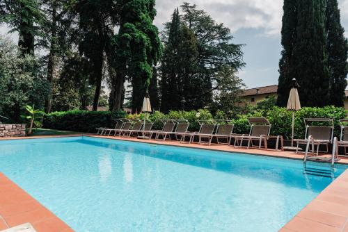 a swimming pool with chairs and umbrellas at Hotel Bellevue in Gardone Riviera