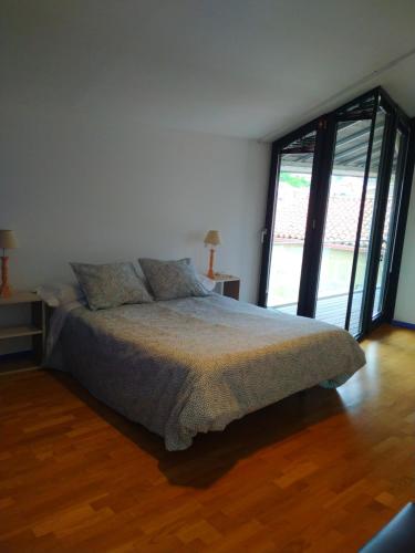 a bedroom with a bed and a large window at Pensión rural Pallabarro in Allariz