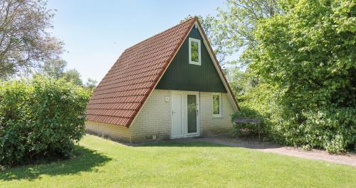 a small yellow house with a brown roof at Bungalows in het Holt in Gramsbergen