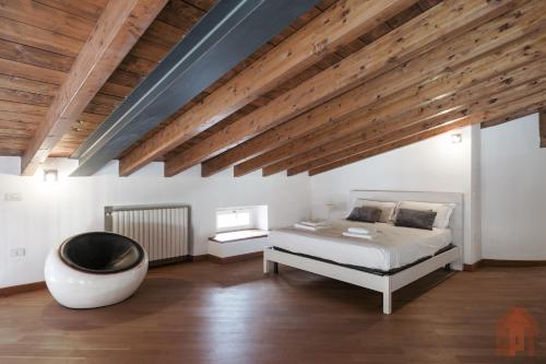 a bedroom with a white bed and a wooden ceiling at Duplex open space with private courtyard in center in Desenzano del Garda