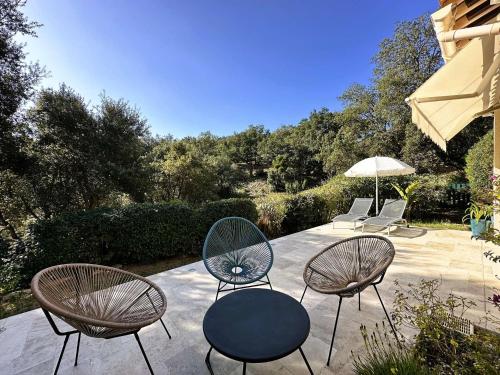 une terrasse avec 3 chaises, une table et un parasol dans l'établissement L'Estagnol, Maison pour 6 personnes à La Londe-les-Maures, à La Londe-les-Maures