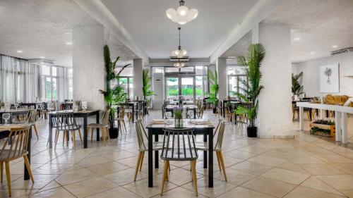 un comedor con mesas, sillas y plantas en The Grove Seaside Hotel, en Dhrepanon