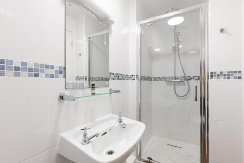 a white bathroom with a sink and a shower at Dunollie Hotel ‘A Bespoke Hotel’ in Broadford