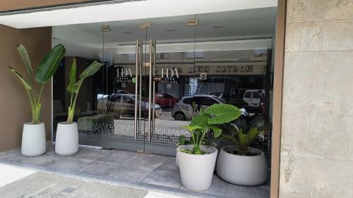 a store window with three white vases with plants in them at HDA Hotel & Spa in Termas de Río Hondo