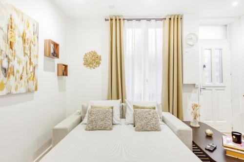 ein weißes Wohnzimmer mit einem Sofa und einem Fenster in der Unterkunft My Home Mirabeau in Malakoff
