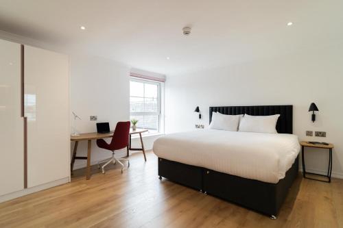 - une chambre avec un grand lit, un bureau et une chaise dans l'établissement PREMIER SUITES Edinburgh Fountain Court, à Édimbourg