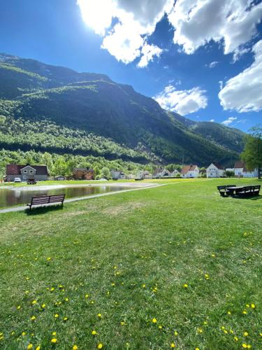 a park with a bench and a river and mountains at Sentralt hus i Rjukan in Rjukan