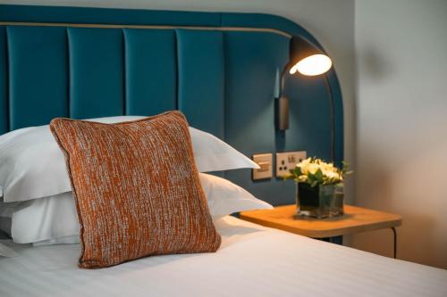 a bed with a pillow and a table with flowers at Waterford Viking Hotel in Waterford
