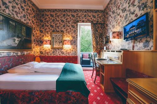 Schlafzimmer mit einem Bett, einem Schreibtisch und einem TV in der Unterkunft Hotel Mittelweg in Hamburg