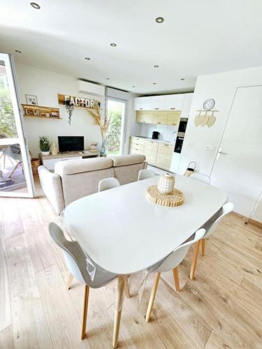 une table blanche et des chaises dans un salon dans l'établissement Mandelieu vacances RDC jardin, piscine, parking 2 chambres, à Mandelieu-la-Napoule