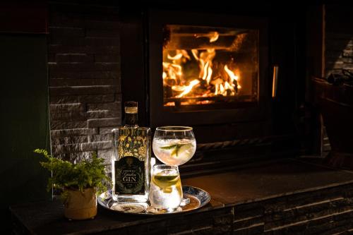 a bottle of beer and a glass of wine in front of a fireplace at Fernhill House Hotel & Gardens in Clonakilty