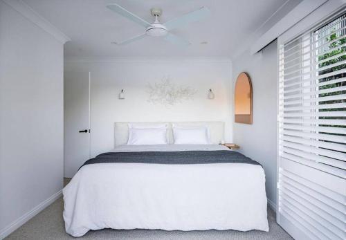 Calabash Bay Lodge في Berowra: غرفة نوم بيضاء مع سرير أبيض ونافذة