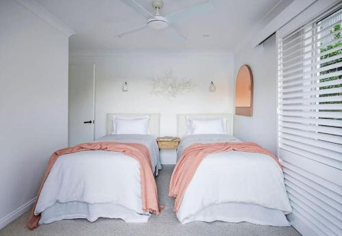 Calabash Bay Lodge في Berowra: سريرين في غرفة بجدران بيضاء