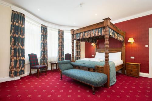a bedroom with a canopy bed and a chair at Crab Hall in Whitby