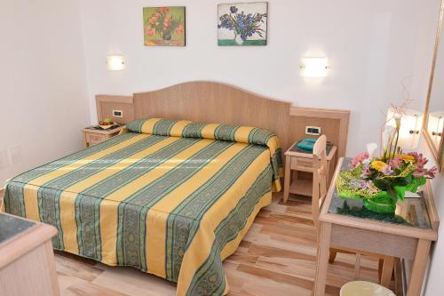 Un dormitorio con una cama y una mesa con flores. en Hotel Thàlas Club, en Torre dell'Orso