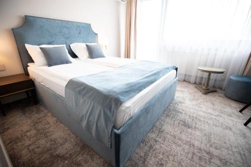 a bedroom with a large bed with a blue headboard at Hotel Meridian in Cluj-Napoca