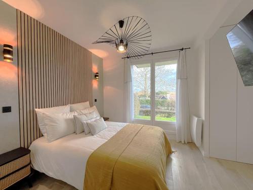 une chambre avec un grand lit et une fenêtre dans l'établissement Le jardin de Deauville, à Deauville