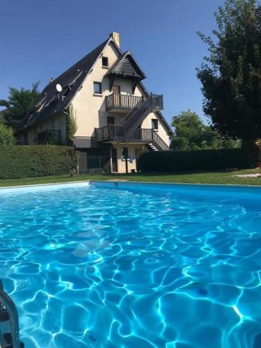 une maison avec une piscine d'eau en face de celle-ci dans l'établissement Le jardin de Deauville, à Deauville