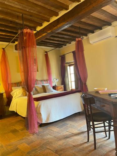 een slaapkamer met een bed met gordijnen en een bureau bij Pienzalettings "Suites" in Pienza