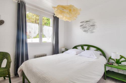 une chambre avec un lit blanc et une fenêtre dans l'établissement Escapade avec jardin à 5 min de la plage, à La Parée Preneau