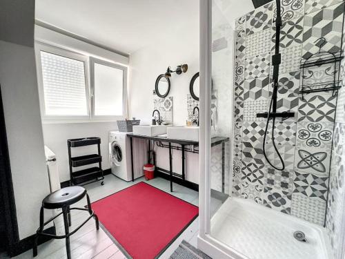 La salle de bains est pourvue d'une douche, d'un lavabo et d'un tapis rouge. dans l'établissement Maison familiale à 700m de la mer avec parking les haubans, à Cayeux-sur-Mer