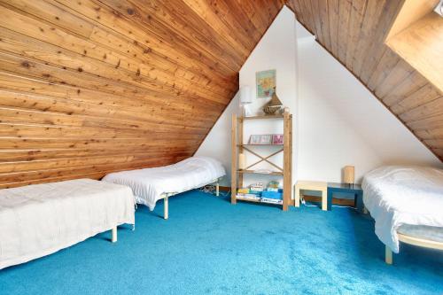 two beds in a room with a wooden ceiling at Vues mer - Accès direct plage - 4 adultes 3 enfants in Erquy