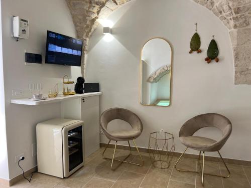 a room with two chairs and a tv and a mirror at Muribel Maison in Ceglie Messapica
