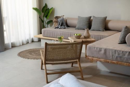 a living room with a couch and a table and chair at Amo Golden Suites in Chrysi Ammoudia