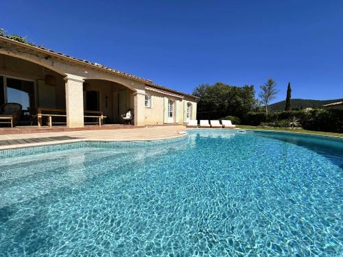 une grande piscine bleue à côté d'une maison dans l'établissement L'Oulivo, Villa pour 10 personnes avec piscine privée dans le Domaine de Valcros à La Londe-les-Maures, à La Londe-les-Maures