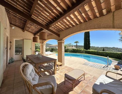 un patio avec une table et des chaises et une piscine dans l'établissement L'Oulivo, Villa pour 10 personnes avec piscine privée dans le Domaine de Valcros à La Londe-les-Maures, à La Londe-les-Maures