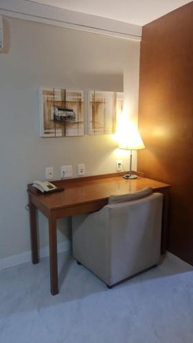 an office with a desk with a lamp and a chair at Flat em Gramado in Gramado