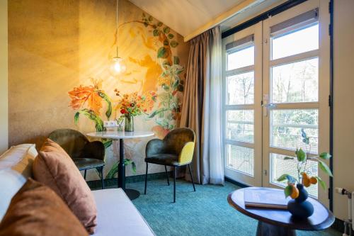 a room with a couch and a table and a window at Parkhotel Tjaarda in Oranjewoud