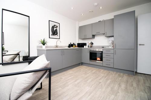 eine Küche mit weißen Schränken und ein Wohnzimmer in der Unterkunft Modern Two BR | Free Parking in Taunton
