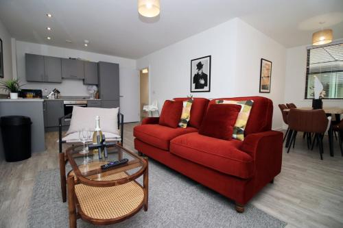 ein Wohnzimmer mit einem roten Sofa und einem Tisch in der Unterkunft Modern Two BR | Free Parking in Taunton