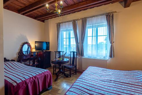 a bedroom with two beds and a tv and a window at Fried Kastély Hotel Simontornya in Simontornya