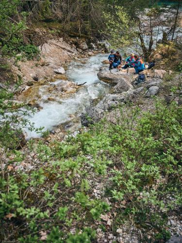 three people sitting on rocks next to a river at Luxury Chalets Gradenbach near Schladming in Haus im Ennstal